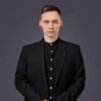 Professional headshot of Kiryl Zaremba in black blazer and shirt against gray background