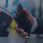 Hand holding mobile payment device near contactless terminal with wireless icon