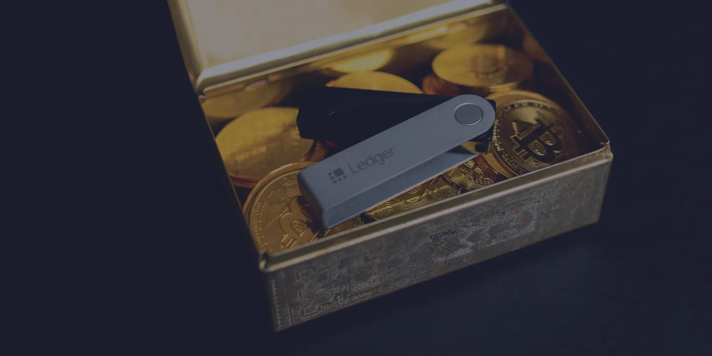 Ledger hardware wallet resting on gold cryptocurrency coins in an open box