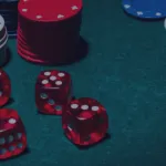 Red dice and stacked poker chips on green gaming table
