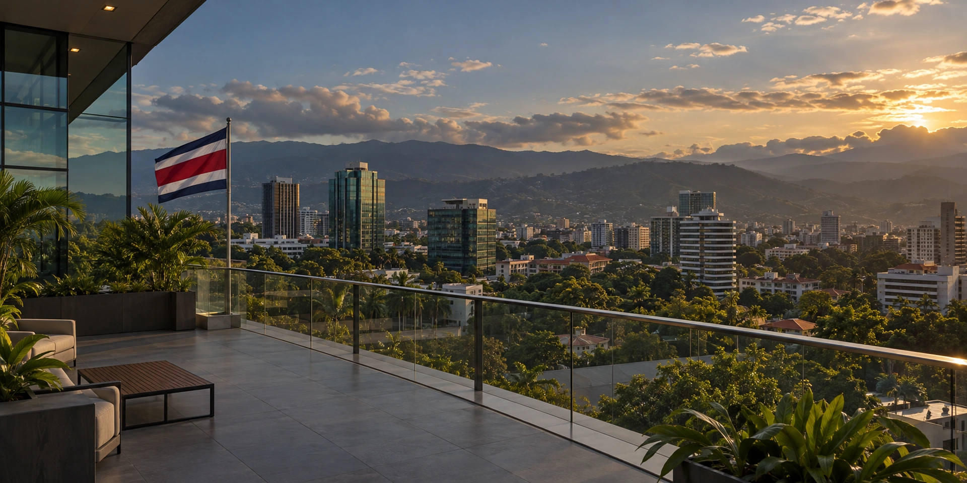 Costa Rican flag on an office terrace overlooking city buildings and tropical mountains at sunset.
